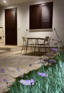 切萨雷奥港Aura Apartments - Orizzonte Turismo的庭院配有桌椅和紫色鲜花