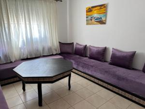 弗尼迪克Appartement F3 en location d'été的客厅配有一张紫色沙发,配有一张桌子