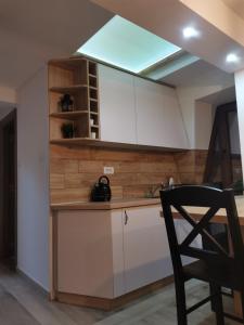迪瓦伊巴雷KATUN Apartmani & SPA的厨房配有白色橱柜和黑椅