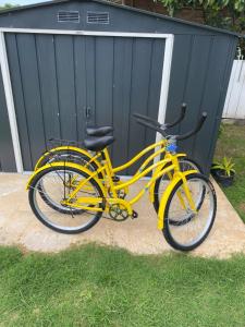 法勒BEE LOCAL LABHOUSE的停在车库旁的草地上的一辆黄色自行车