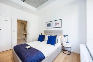 伦敦Apartment Near Canary Wharf 02 Arena & Excel的白色卧室配有一张带蓝色枕头的大床