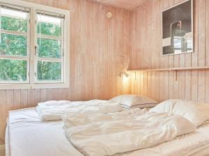 维斯特索马肯Holiday home Aakirkeby LXIII的一张白色大床,位于带木墙的房间
