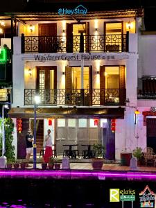 马六甲Wayfarer Guest House Jonker Street Melaka By Heystay Management的两人晚上在旅馆前行走