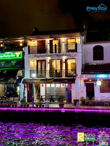 马六甲Wayfarer Guest House Jonker Street Melaka By Heystay Management的水体前方有紫色灯的建筑