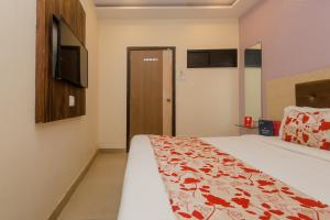 孟买Hotel Golden Nest Near Chhatrapati Shivaji International Airport的卧室配有一张床,墙上配有电视。