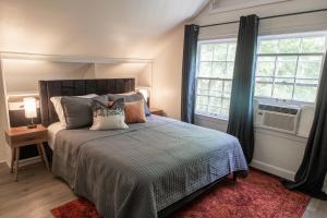 孟菲斯J Birds' Cottage Midtown Memphis的一间卧室设有一张床和两个窗户。