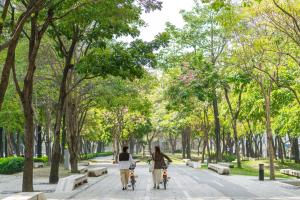 台中市全国大饭店的两个人骑着自行车沿着公园的人行道走下去