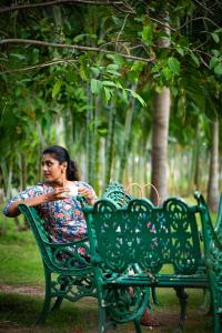 哥印拜陀Ibex River Resort, Pollachi的坐在公园绿凳上的女人