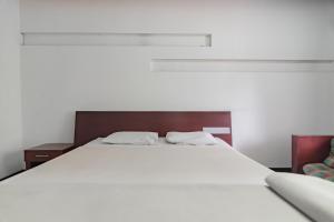 万隆Istana Hotel Bandung Mitra RedDoorz的一张白色的大床,上面有两个白色的枕头