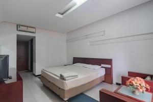 万隆Istana Hotel Bandung Mitra RedDoorz的一间卧室配有一张床和一台电视。