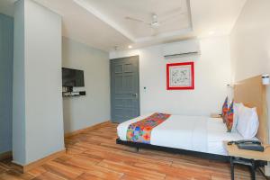 新德里FabExpress PP Residency的一间卧室配有一张床、一张书桌和一台电视。