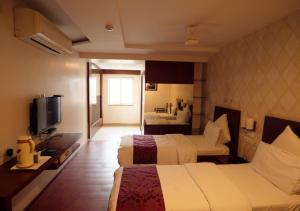 卡努尔Hotel Sasya Pride的酒店客房设有两张床和电视。