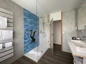 博登斯边的伊门施塔特水岸埃伯尔酒店的浴室配有淋浴和墙上的黑天鹅