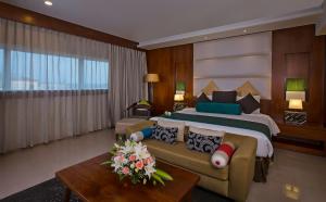 科泽科德拉维兹卡利卡特酒店的一间卧室配有一张大床和一张沙发
