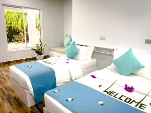 福拉杜岛Island Luxury Dive Hotel - Fulhadhoo的两张位于酒店客房的床,上面有鲜花