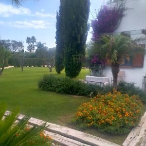 蒙德拉戈内Hotel & Resort Lunatenuta的一座花园,在一座建筑前方,花园内有长凳和鲜花