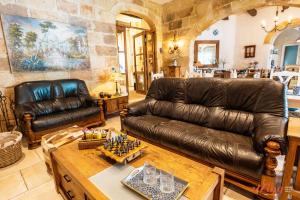 ŻebbuġRest, restore, explore. An exclusive stay in Malta的客厅配有真皮沙发和桌子