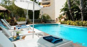 ŻebbuġRest, restore, explore. An exclusive stay in Malta的一个带桌子和遮阳伞的游泳池