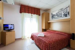 利多迪耶索罗滨海酒店的一间卧室配有红色的床和电视