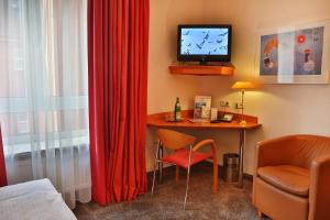 汉堡Hotel AM ELBUFER的客房设有书桌、电视和椅子