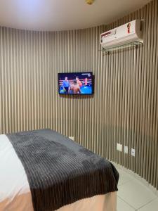纳塔尔Flat Beira Mar- Ap 306 #ELEGANCE的卧室配有一张床,墙上配有电视。