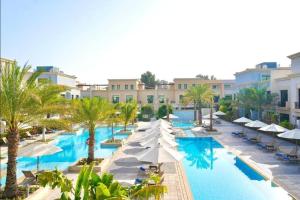 阿布扎比Andalus Al Seef Resort & Spa的一个带遮阳伞和棕榈树的游泳池的度假酒店
