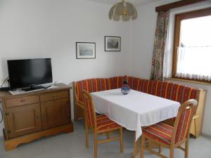 利恩茨Haus Jeller的一间设有白色桌子和电视的用餐室