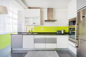 奥埃拉斯Santo Amaro Beach Family Stays的一间拥有白色橱柜和绿色装饰的厨房