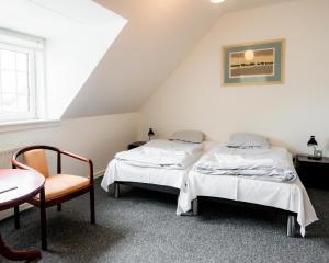 岑讷Abild Kro & Hotel的配有一张桌子和一把椅子的客房内的两张床