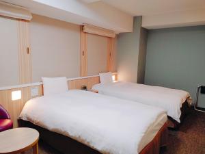 松江市多美迎EXPRESS松江酒店的酒店客房设有两张床和一张桌子。