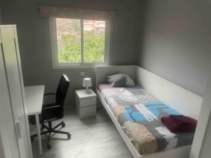 大加那利岛拉斯帕尔马斯Casa Nueva的一间卧室配有一张床、一张书桌和一个窗户。