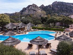 巴哈撒丁岛白鹭酒店的一个带椅子和遮阳伞的游泳池以及山地