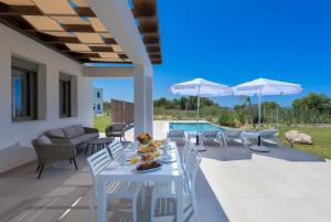 塞奥洛戈斯Panaxia Villas的一个带游泳池的庭院里配有一张白色的桌子和椅子