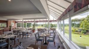 百利科内尔斯利福罗赛尔酒店的餐厅设有桌椅和大窗户。