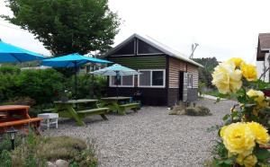 襄阳郡Amigas Ocean View Pension的一个带野餐桌和遮阳伞的花园以及一间小屋
