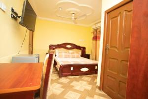 库马西Glory Hills Hotel的一间卧室配有一张床、一张桌子和一台电视。