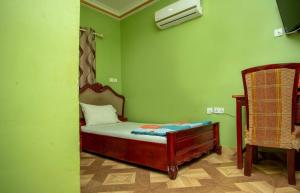 库马西Glory Hills Hotel的小型绿色客房配有床和椅子