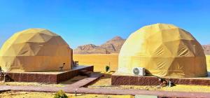 瓦迪拉姆Darien Luxury Camp的沙漠中的两顶圆顶帐篷,背景为山脉