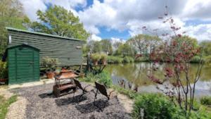 阿克菲尔德Snug & Secluded Lakeside Shepherds Hut 'Carp'的湖畔野餐桌和长凳