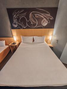 里约热内卢宜必思里约热内卢中央酒店的卧室配有一张白色大床,墙上挂有绘画作品