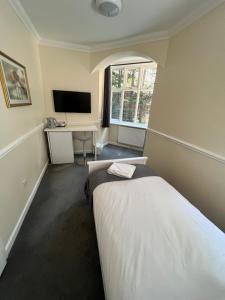 布拉克内尔阿德默勒旅馆的一间卧室配有一张床、一张书桌和一台电视