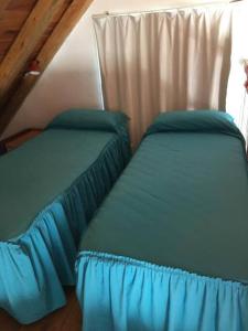 圣拉斐尔Casa en Los Reyunos, Ubicación perfecta Frente al lago的阁楼卧室配有两张带蓝色床单的床