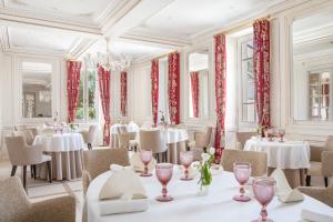 科涅克La Nauve, Hôtel & Jardin - Relais & Châteaux的餐厅配有白色的桌椅和红色的窗帘