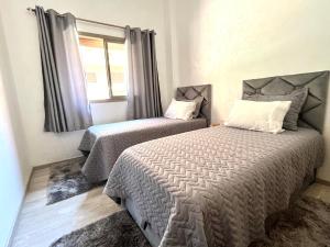 马拉喀什ASAMA appartement avec piscine的一间卧室设有两张床和窗户。