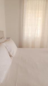 StavrosSpilia的卧室内的一张白色床,设有窗户