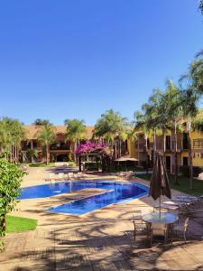 索里苏Imperial Palace Hotel Sorriso的一个带桌椅的度假村游泳池,并种植了棕榈树