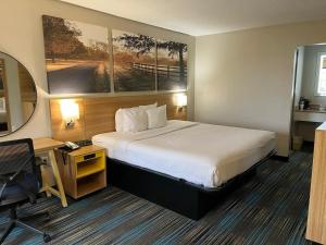 莫比尔提尔曼斯角Days Inn & Suites Mobile的酒店客房配有一张床、一张书桌和一张四柱床