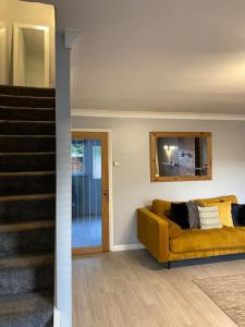 达灵顿Comfy Darlington Home的客厅设有黄色沙发和楼梯。