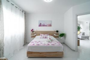 内尔哈Casa Higuera的白色卧室配有带粉红色床单的床