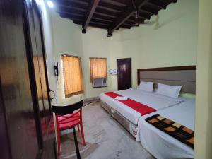 普里Hotel Surya Greens的一间卧室配有两张床和红色椅子